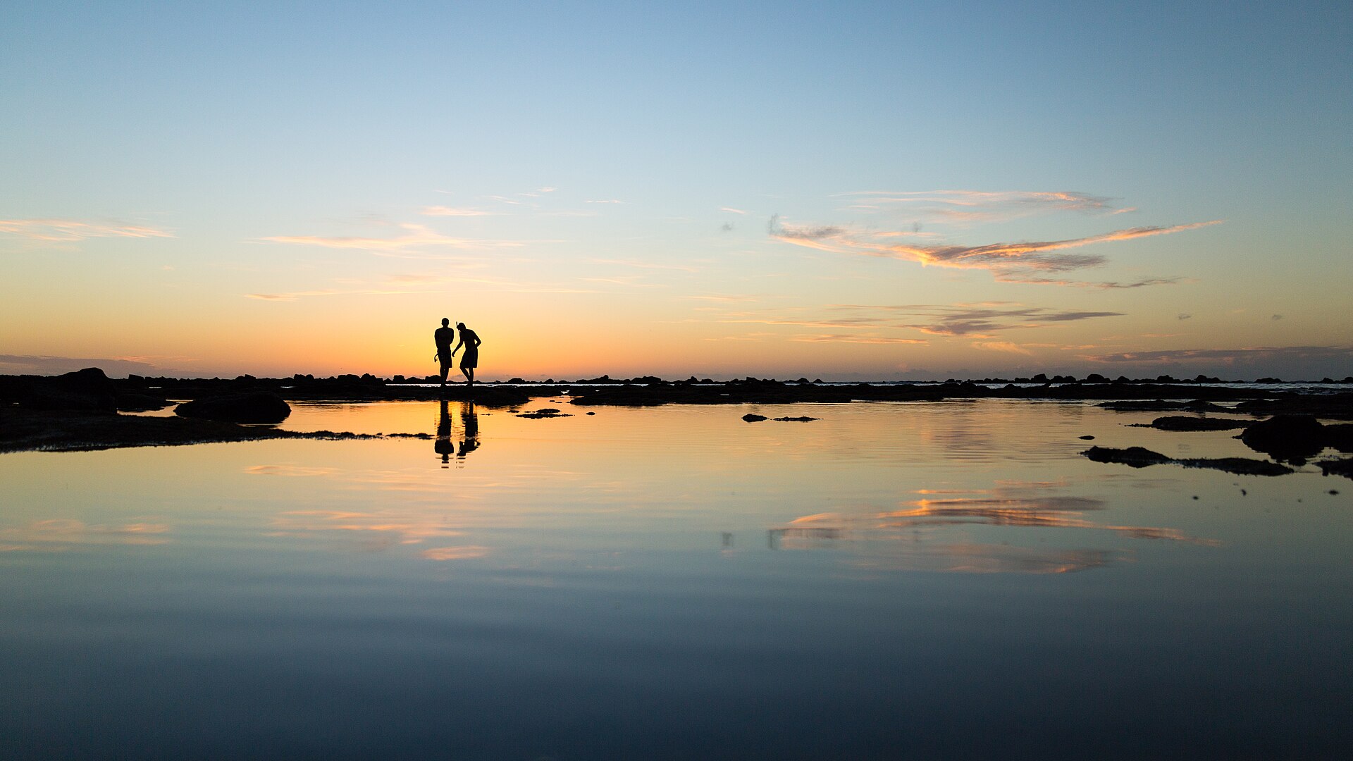 A couple looking toward the horizon at sunset